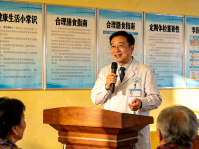 健康管理专家李医生 - 在社区健康讲座上演讲，背后是健康宣传海报