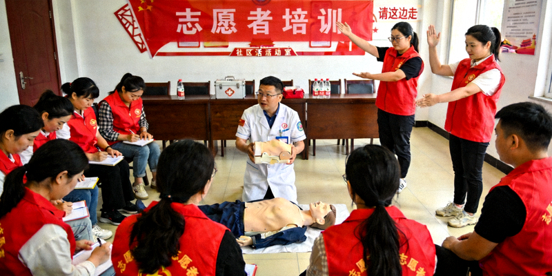 志愿者培训现场照片 - 身穿统一服装的志愿者在学习急救知识与引导手势