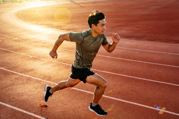 户外跑道上奔跑的跑者，阳光洒在跑道上