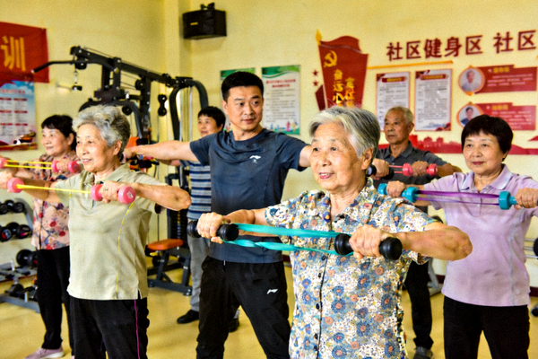 社区健身课堂上居民跟随教练完成力量训练动作