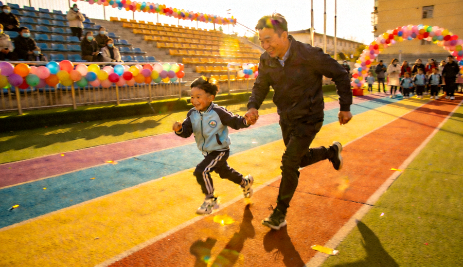 亲子趣味运动会上家长与孩子在跑道上奔跑的欢乐场面