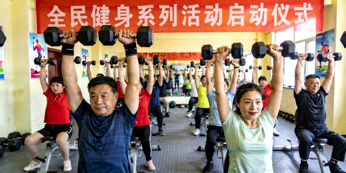 全民健身系列活动启动现场，市民在健身房内使用哑铃进行力量训练